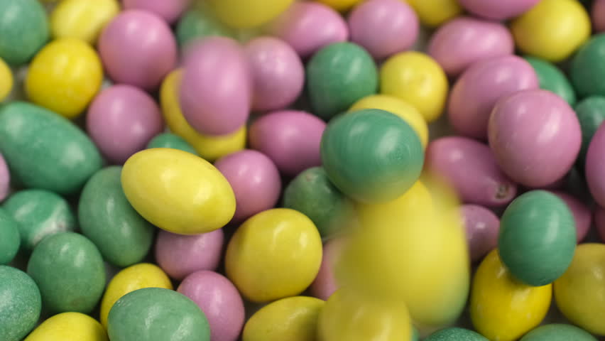Multicolored dragee candies falling down on heap close up. Assorted colorful chocolate candies