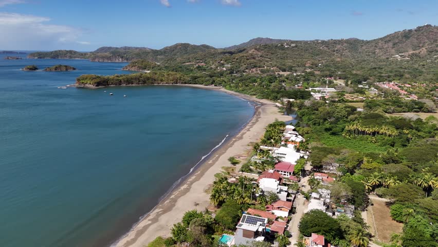 Aerial revealing shot of Costa Rica coastline with beachfront homes overlooking the Pacific Ocean and scenery