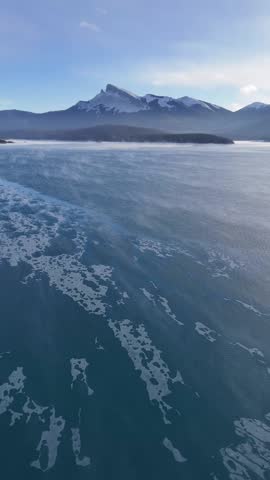Drone panorama of snow-covered hills and frozen lake stretching into the distance in Alberta