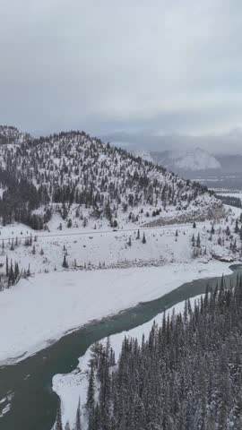 Drone shot of snow-covered ice shelf extending into turquoise lake water in Alberta’s winter landscape