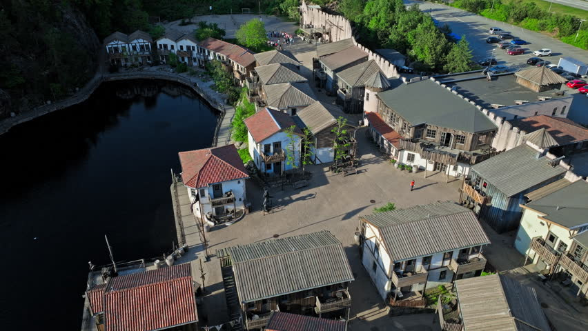 The fortified walls, wooden pirate houses, canals, lighthouse, and surrounding forested landscape are all characteristic features of Abra Havn, a themed harbour area along the Topdalsfjorden.