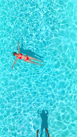 Top down view as a man dives into the pool while woman is laying on her back