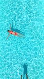 Top down view as a man dives into the pool while woman is laying on her back - Powered by Shutterstock - Get 15% off with code: PIKWIZARD15