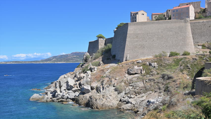 The Calvi fortress stands on a rocky coast, overlooking the blue water. Corsica, France