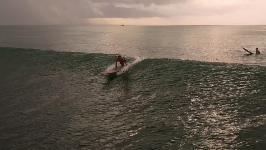 Dusk Longboard Rider Cruising Mellow Wave Under Soft Pastel Sky With Reflective Water And Distant Paddlers