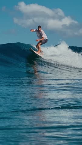 Surfer Carving Wave At Reef Under Bright Blue Sky, Powerful Barrel Forming, Foamy Spray Flying, Dynamic Turns,Vertical video