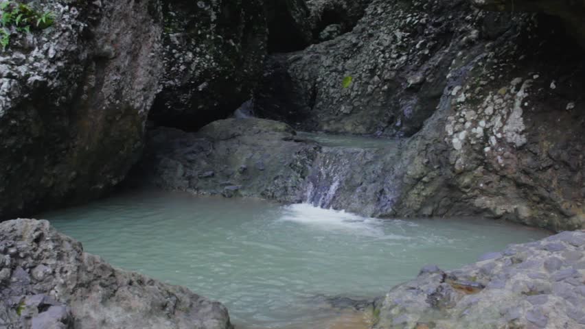 Small waterfall flowing over mossy river rocks