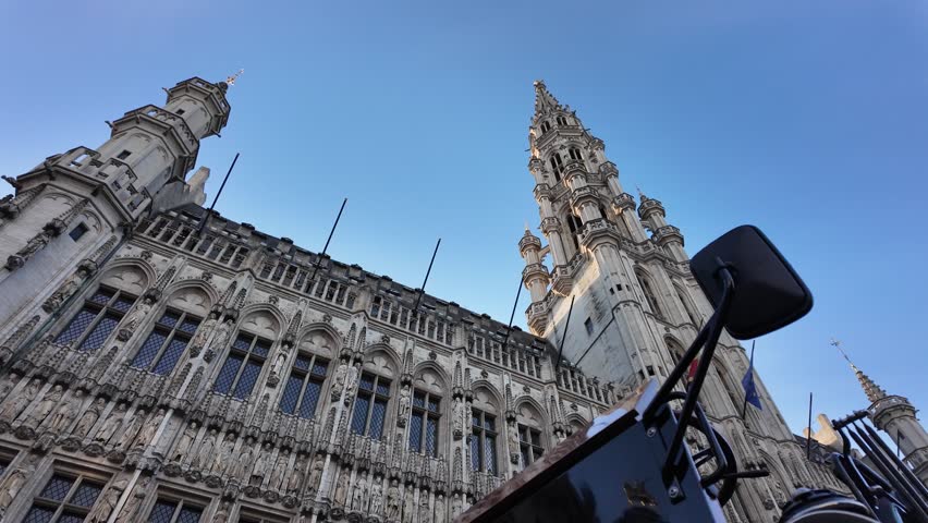 Slow motion view of an electric tourist carriage passing in front of Brussels Town Hall on Grand Place.