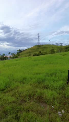 Person Walking on Grassy Field Under Cloudy Sky