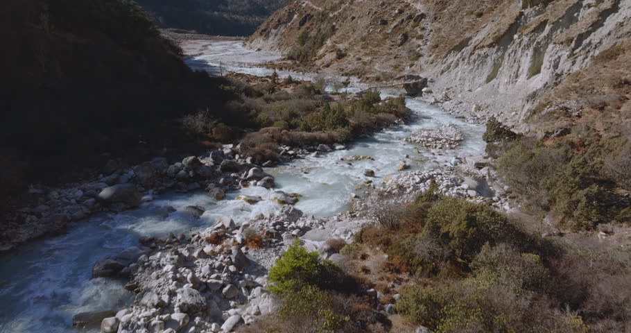 River flowing through the base of the Himalayan mountains along the Everest Base Camp trek route in Nepal. Scenic alpine waterway set within a dramatic high-altitude landscape.