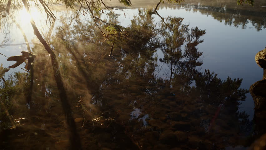 Cinematic view of river surface with soft reflections and mist rising from the water