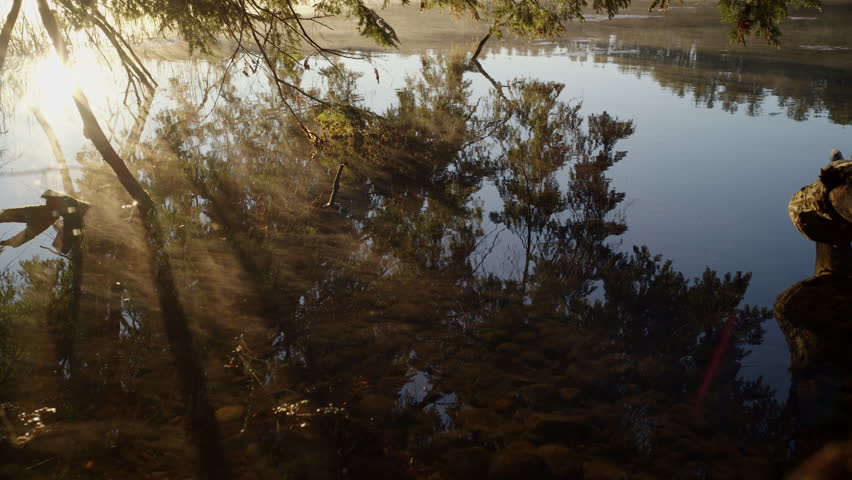 cinematic shot of surface of river with reflection and mist rising off the river