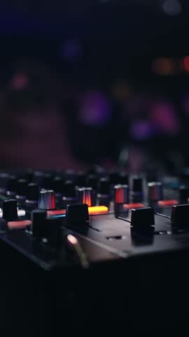 Close-up of illuminated DJ mixer and turntable at night, colorful club lights glowing in the blurred background, capturing an atmospheric electronic music performance