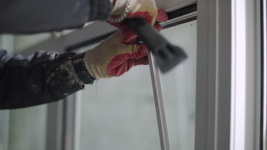 Worker installing glazing bead while fixing glass in window frame