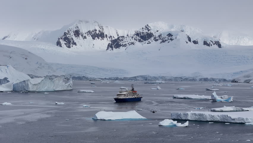 Expedition cruise ship navigating amidst icebergs in antarctica