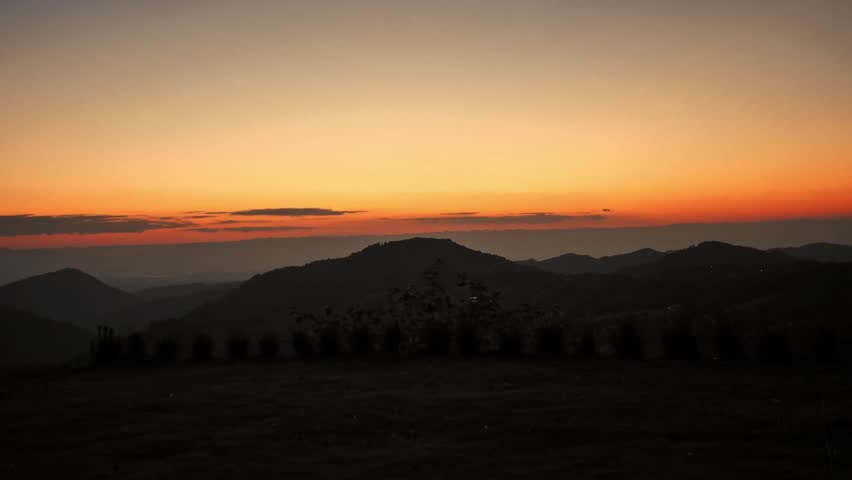 A silhouette of a men walking and admiring the mountain view during a dramatic sunset. This peaceful outdoor scene captures a sense of freedom and inspiration in the beautiful wilderness at dusk.