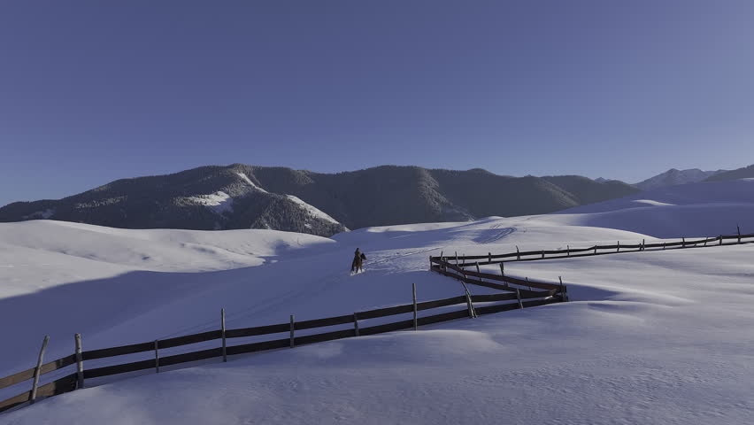 Person riding a horse through a pristine snowy landscape in Kazakhstan
