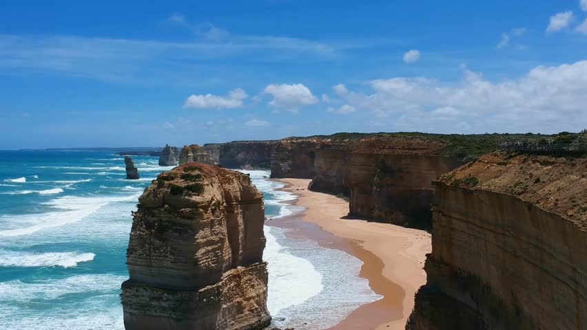 This breathtaking 4K footage captures the Twelve Apostles, a world-famous collection of limestone stacks located off the coast of Port Campbell National Park in Victoria, Australia. Formed by centuries of relentless erosion from the Southern Ocean, these massive pillars rise up to 45 meters (150 feet) from the turquoise waters. The video showcases the dramatic contrast between the rugged mainland cliffs and the isolated stacks, illustrating the raw power of geological change. Although named the "Twelve Apostles," only seven stacks remain today following natural collapses over time. This scenic landmark along the Great Ocean Road is a premier symbol of Australia