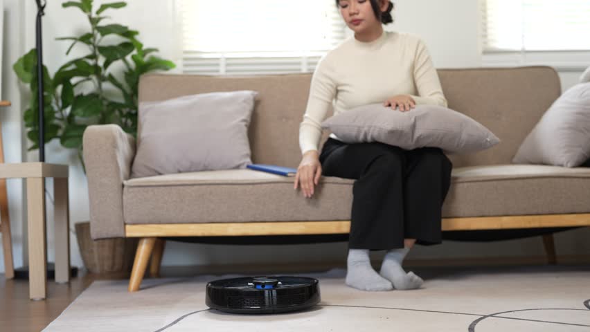 Woman turns on smart robot vacuum cleaner