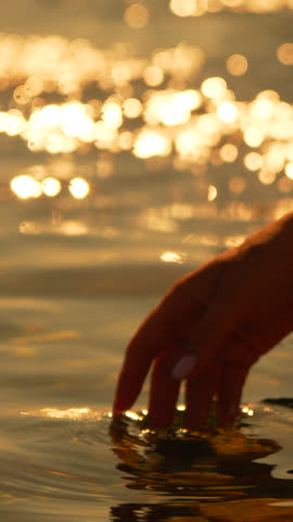 Hand water sunset golden hour touch ripples romantic surface Vertical video