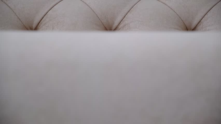 Detail of upholstery of modern furniture, chair, armchair, cushion, pillow. Carriage coupler. Premium luxury fabric. Details of furniture. Design interior. Beige light pink, neutral color backdrop.