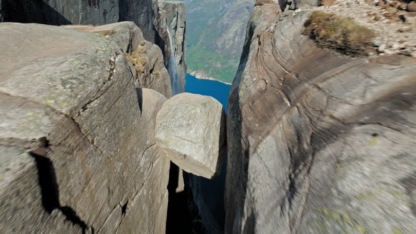 Aerial drone view through towering granite cliffs at Kjerag above Lysefjord in Norway. Deep fjord waters framed by dramatic rock walls on a clear summer day, highlighting iconic Nordic wilderness.