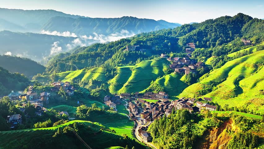 Aerial shot of beautiful green rice terrace fields and villages with mountain natural landscape in Guilin, China. 