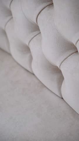 Detail of upholstery of modern furniture, chair, armchair, cushion, pillow. Carriage coupler. Premium luxury fabric. Details of furniture. Design interior. Beige light pink, neutral color backdrop.