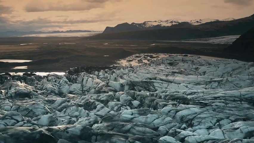 Aerial view of Iceland’s ice lagoon at sunset, flying over Vatnajökull glacier with volcanic ash, showcasing dramatic landscapes and natural beauty.