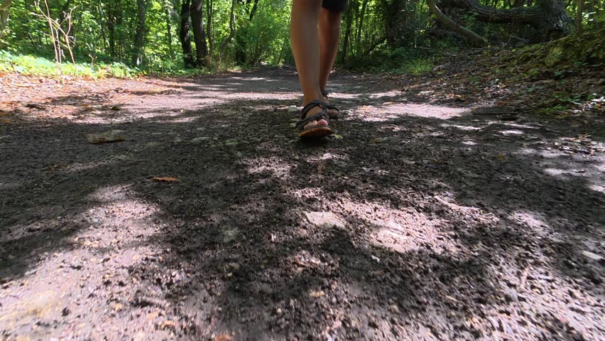 Low-angle close-up of child s feet walking along forest trail. Peaceful outdoor hike through green woodland, showing movement, nature connection and slow travel lifestyle