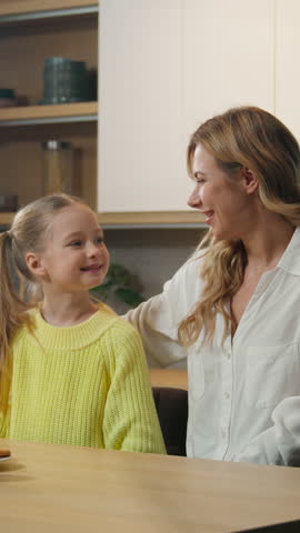 Caucasian family at kitchen hug happy cute adopted little girl child kid with mother woman babysitter hugging cuddle mom cuddling mum embracing daughter enjoy dinner at home breakfast time together