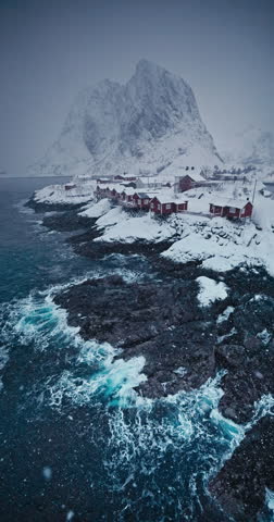 Winter panorama landscape of Reine village, Lofoten islands, Norway, rocky coast and snowy mountains peaks and cinematic snowing video
