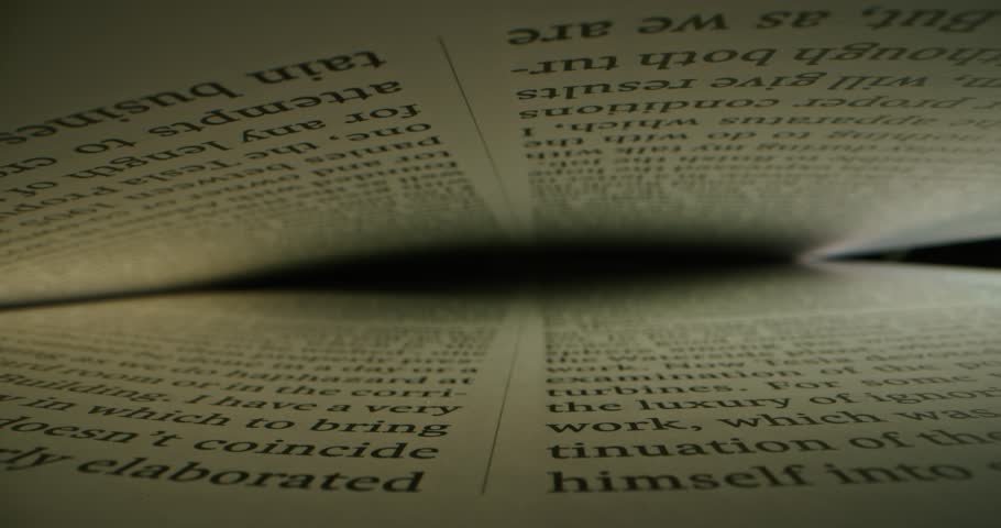 Extreme close-up view of a text in English between the pages in a book, shot inside a book with laowa probe lens with dolly shot. Sliding over lines with text. Reading book. Macro shot