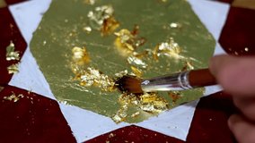Detailed shot of gold leaf application on a wooden star, using a brush to gently lay and smooth the delicate gold flakes, creating a luxurious and handcrafted decorative item with painstaking - Powered by Shutterstock - Get 15% off with code: PIKWIZARD15