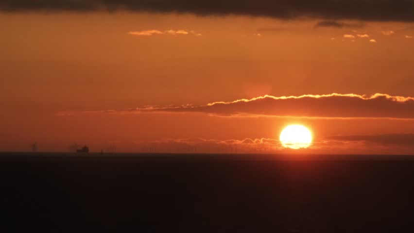 4K time-lapse footage of a stunning sunset over the North Sea near the Dutch coastline. The sky glows with vibrant transitions as the sun sinks below the ocean, creating a peaceful and cinematic mood.