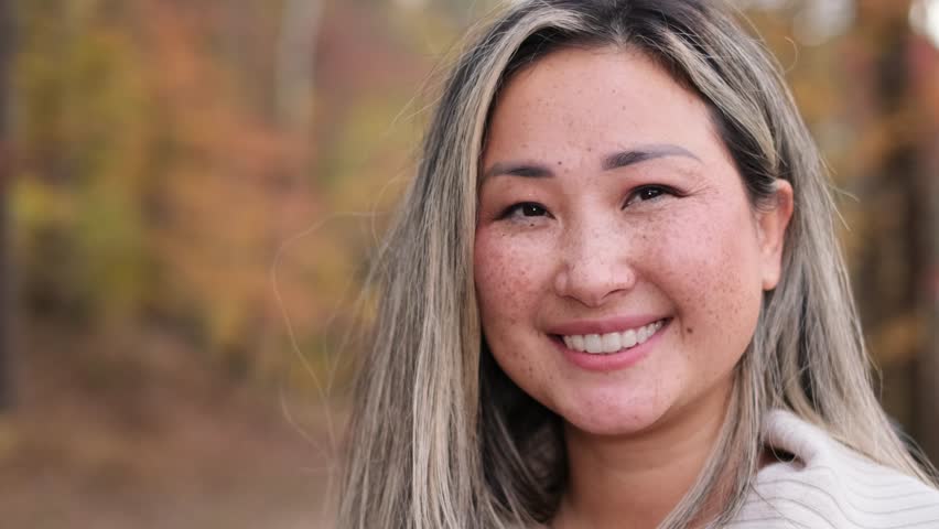 Beautiful asian woman with freckles smiling outdoors