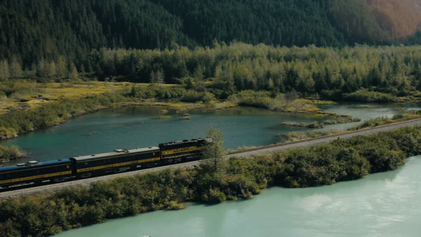 Medium aerial tracking shot of the Alaska railroad as it makes its way to Whittier Alaska.