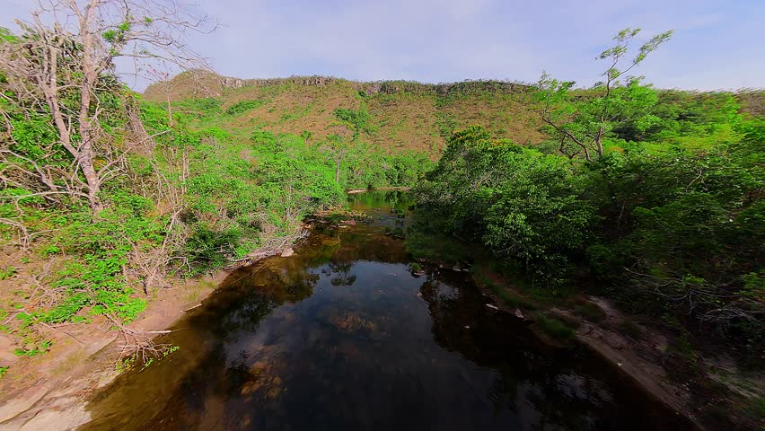 Low-altitude FPV drone sequence along the Rio dos Couros in the Chapada dos Veadeiros, Brazil showcasing highlight the gnarled Canela-de-ema shrubs and crystalline pools of the Goiás highlands.