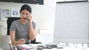 Designer working in office and making call on mobile phone. Female interior designer talking by mobile phone at desk in office. - Powered by Shutterstock - Get 15% off with code: PIKWIZARD15