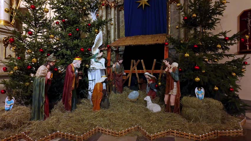 Christmas nativity scene inside church with Holy Family figures Christmas trees festive religious decorations during celebration