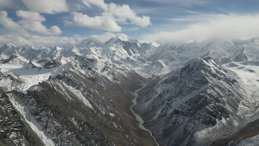 Majestic mountain landscape showcasing snow-capped peaks and a winding river below, as the camera pans across the breathtaking scenery, revealing the vastness of nature