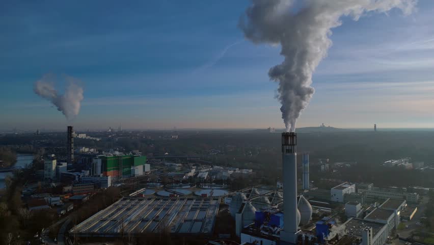 Urban waste to energy plant featuring large chimneys emitting steam into a clear blue sky, illustrating sustainable urban development. Great aerial view panorama overview drone