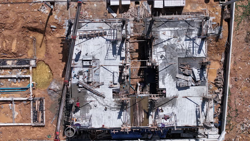 Top-down 4K drone timelapse showing laborers working on a building site, preparing rebar and concrete for a new residential home foundation.