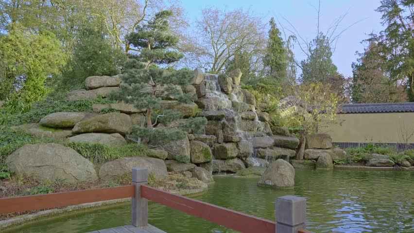 Wide view of the Chinese garden natural rocky waterfall in Maurepas park environment, Rennes, Ille-et-Vilaine, France