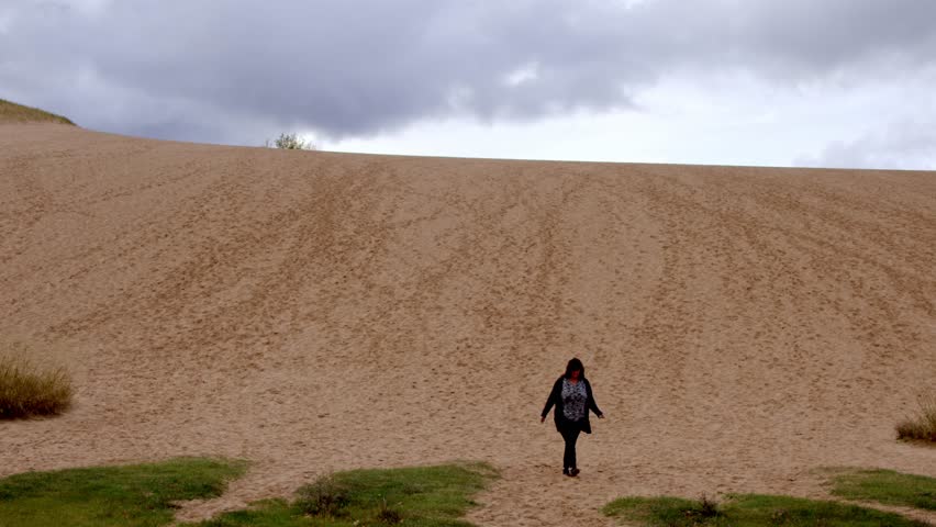 Middle aged woman walking down the Dune Climb at the Sleeping Bear Dunes National Lakeshore in Michigan on an autumn day with stable video.