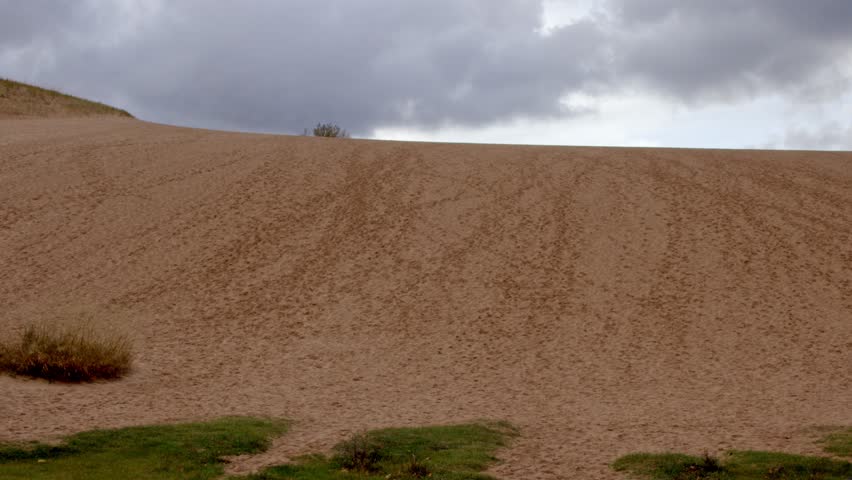 Middle aged woman walking up the Dune Climb at the Sleeping Bear Dunes National Lakeshore in Michigan on an autumn day with stable video wide shot.