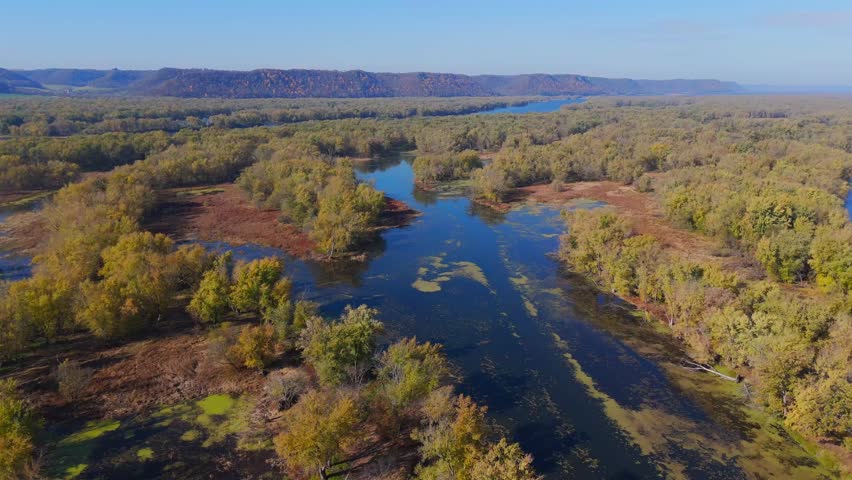 Fall foliage glows across floodplain wetlands and wooded islands under clear skies. Wisconsin