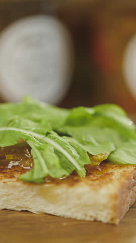 Close-up of a handcrafted sandwich with cured ham, cheese and arugula on crispy bread, in a blurred gastronomic setting.