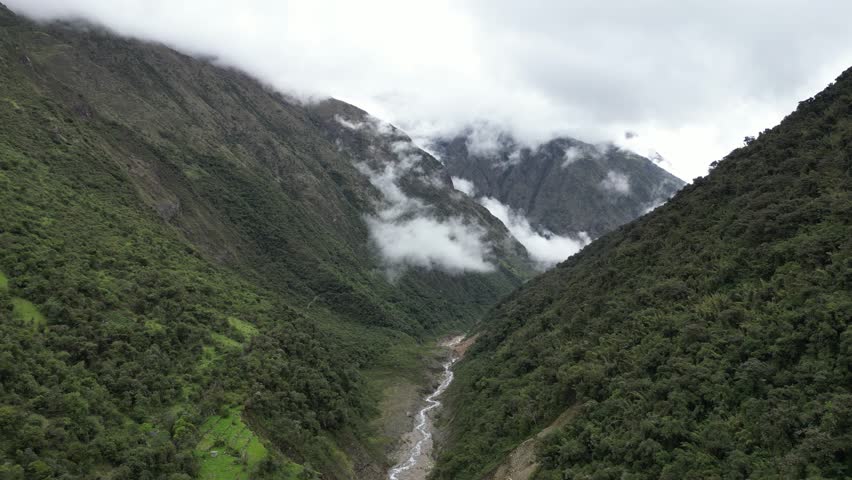 Ethereal mist fills a mountain valley in the Andes, river flowing beneath shifting clouds.