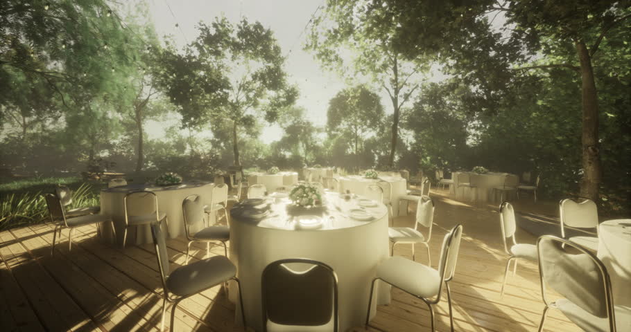 Tables are arranged for a special event in a serene outdoor setting surrounded by lush trees. Sunlight filters through leaves, creating a warm atmosphere for guests.